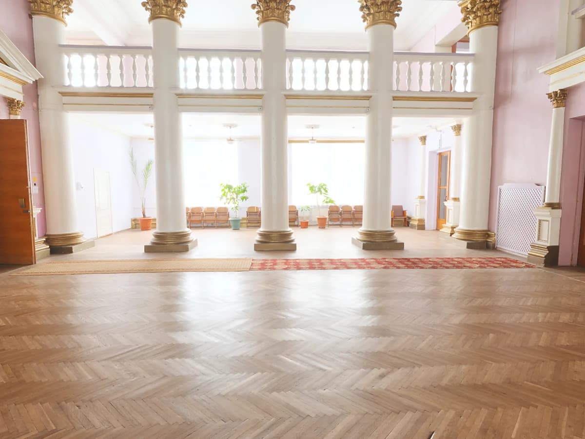 Light-filled reference vestibule with classical columns, parquet flooring and a window-facing seating area