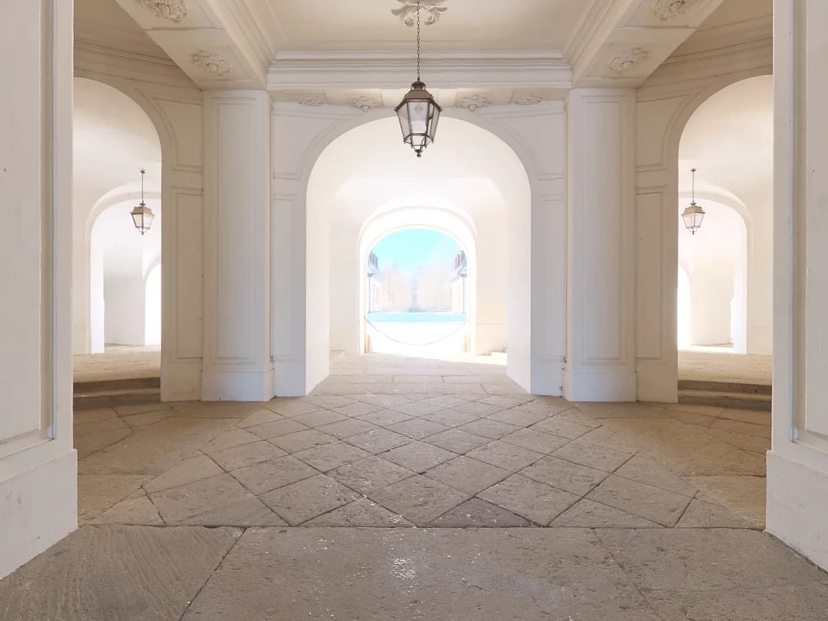 Light-filled architectural arcade with stone floors and a clear view through successive arches